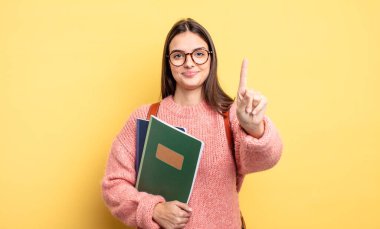 pretty student woman smiling and looking friendly, showing number one
