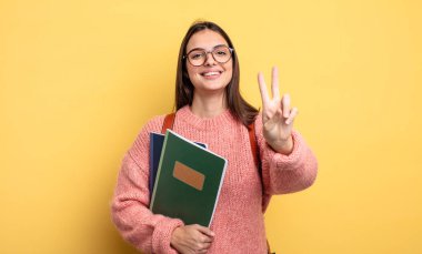 pretty student woman smiling and looking friendly, showing number two