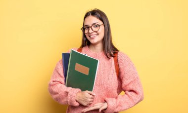 pretty student woman smiling cheerfully, feeling happy and showing a concept