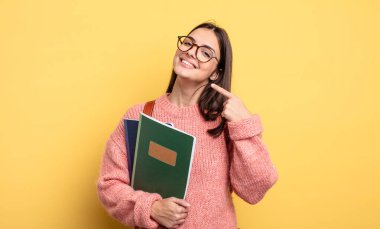 pretty student woman smiling confidently pointing to own broad smile