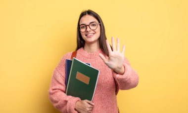 pretty student woman smiling and looking friendly, showing number five