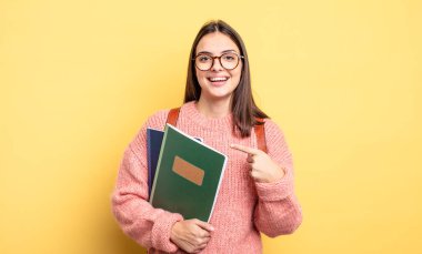 pretty student woman looking excited and surprised pointing to the side