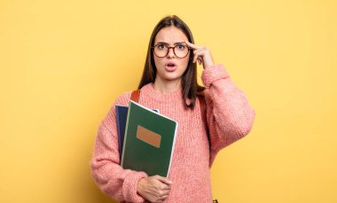 pretty student woman looking surprised, realizing a new thought, idea or concept
