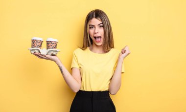 Güzel kadın şokta, gülüyor ve başarıyı kutluyor. kahve konseptini kaldır.