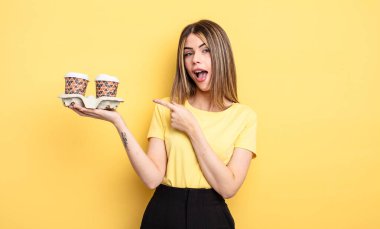 Güzel bir kadın heyecanlı ve şaşırmış görünüyor. kahve konseptini kaldır.