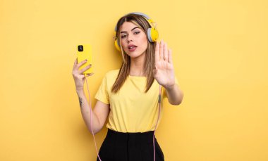 Ciddi görünüyor. Avuç içini gösteriyor. Dur hareketi yapıyor.