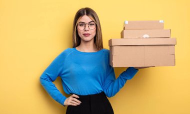 pretty woman smiling happily with a hand on hip and confident packages boxes concept