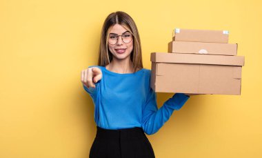 pretty woman pointing at camera choosing you packages boxes concept