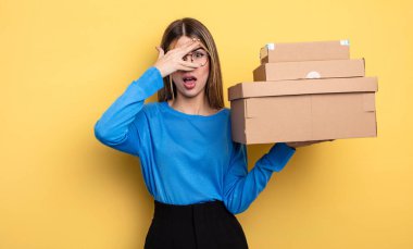 pretty woman looking shocked, scared or terrified, covering face with hand packages boxes concept