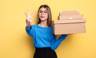 Güzel bir kadın gülümsüyor ve arkadaş canlısı görünüyor. Üç numaralı paket kutusu konseptini gösteriyor.