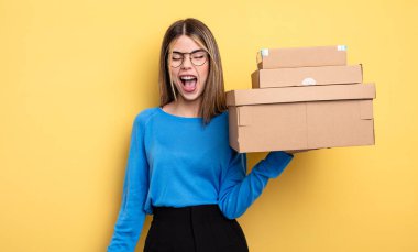 Güzel bir kadın agresif bir şekilde bağırıyor, kızgın paket kutuları konseptine bakıyor.