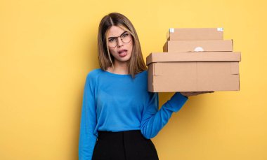 Güzel bir kadın, kafası karışık ve kafası karışık paket kutuları konseptini hisseder.