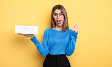 Güzel kadın şokta, gülüyor ve başarıyı kutluyor. Beyaz kutu tutuluyor