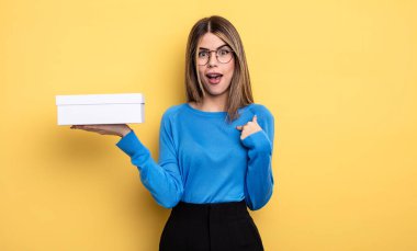 Güzel bir kadın mutlu hissediyor ve heyecanla kendini işaret ediyor. Beyaz kutu tutuluyor