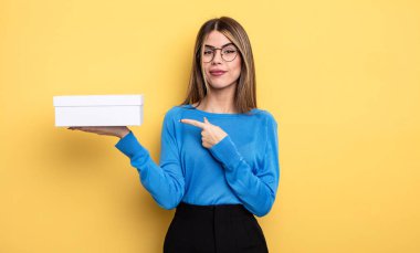 Güzel bir kadın neşeyle gülümsüyor, mutlu hissediyor ve bir tarafı işaret ediyor. Beyaz kutu tutuluyor