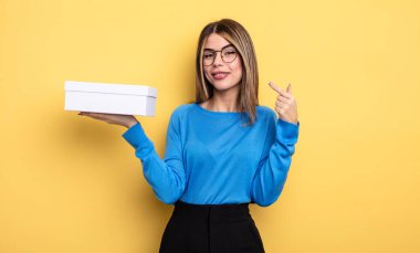 Kendine güvenen güzel bir kadın kendi gülüşünü işaret ediyor. Beyaz kutu tutuluyor