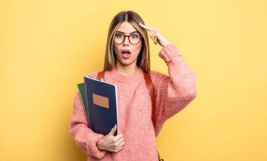 Güzel bayan öğrenci şaşırmış görünüyor, yeni bir düşünce, fikir ya da konsept fark ediyor. kitaplar ve sırt çantası