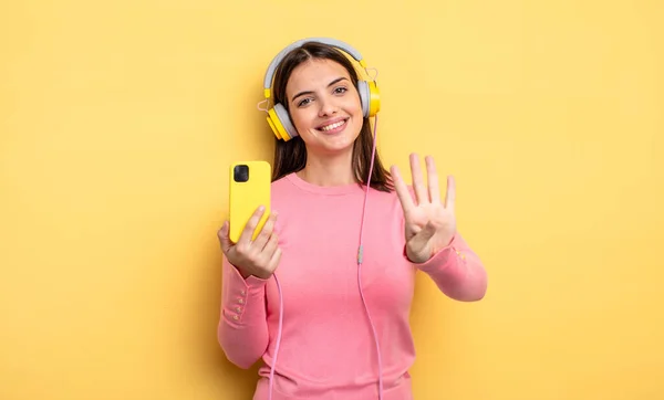 Pretty Woman Smiling Looking Friendly Showing Number Four Listening Music — Stockfoto