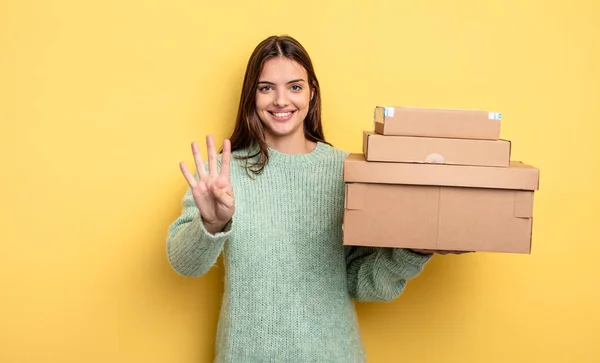 Mooie Vrouw Glimlachend Zoek Vriendelijk Tonen Nummer Vier Pakketten Dozen — Stockfoto