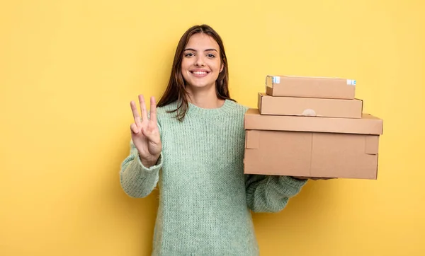 女性は笑顔で親しみやすく3つのパッケージボックスのコンセプトを示し — ストック写真