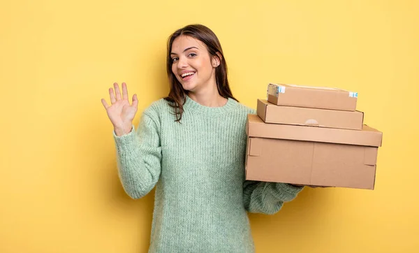 Pretty Woman Smiling Happily Waving Hand Welcoming Greeting You Packages — Stockfoto