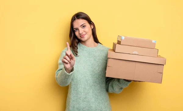 Pretty Woman Smiling Looking Friendly Showing Number One Packages Boxes — Fotografia de Stock