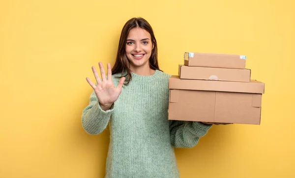 Pretty Woman Smiling Looking Friendly Showing Number Five Packages Boxes — Stock Photo, Image