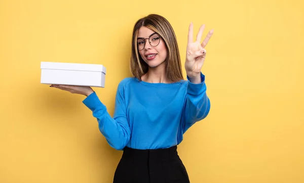 Mujer Bonita Sonriendo Buscando Amigable Mostrando Número Tres Sosteniendo Caja — Foto de Stock