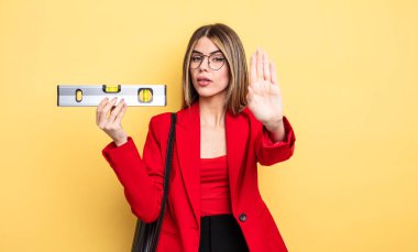 Mimar kadın ciddi görünüyor. Avuç içi gösteriyor. Jesti durduruyor ve dengeyi sağlıyor.