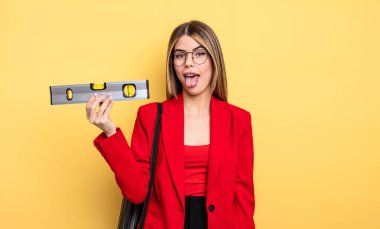 Neşeli ve asi tavırlı mimar kadın, şaka yapıyor, dilini dışarı çıkarıyor ve dengeyi sağlıyor.