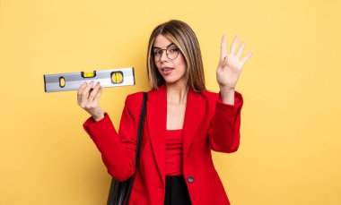 Mimar kadın gülümsüyor ve arkadaş canlısı görünüyor, dört numarayı gösteriyor ve dengeyi sağlıyor.