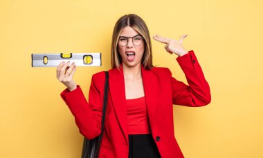 Mimar kadın mutsuz ve stresli görünüyor, intihar jesti silah işareti yapıyor ve dengesini koruyor.