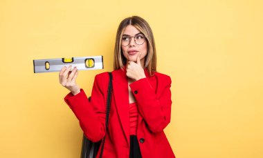 Mimar kadın düşünüyor, kuşkulu hissediyor, kafası karışık ve dengeyi koruyor.