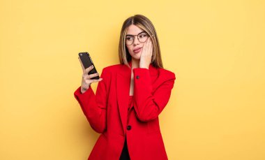 İş kadını yorucu bir işten sonra sıkılmış, hayal kırıklığına uğramış ve uykulu hissediyor. akıllı telefon kavramı