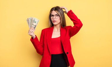 İş kadını şaşkın ve kafası karışık, kaşınan bir kafa hissediyor. Dolar banknotları konsepti