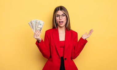 İş kadını kendini mutlu hissediyor, bir çözüm ya da fikir bulduğuna şaşırıyor. Dolar banknotları konsepti