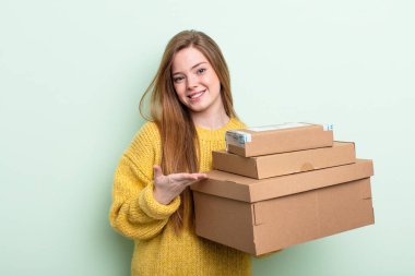 Kızıl saçlı kadın neşeyle gülümsüyor, mutlu hissediyor ve bir konsept gösteriyor. paket kutuları konsepti