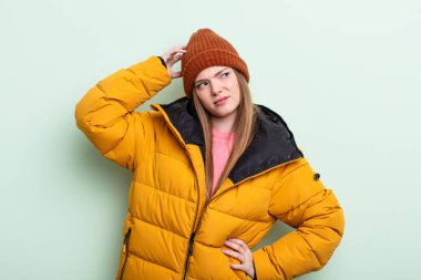 Kızıl saçlı kadın şaşkın ve kafası karışık, kaşınan kafa. kış konsepti