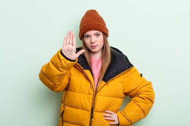 Kızıl saçlı kadın ciddi görünüyor. Avuç içini gösteriyor. Durdurma hareketi yapıyor. kış konsepti