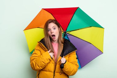 Şok olmuş ve ağzı açık, kendini gösteren kızıl saçlı bir kadın. şemsiye kavramı