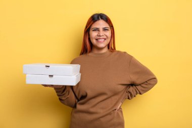 İspanyol kadın mutlu bir şekilde gülümsüyor, eli kalçasında ve kendinden emin. Pizza konseptini kaldır.