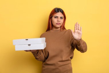 İspanyol kadın ciddi görünüyor. Avuç içini gösteriyor. Durdurma hareketi yapıyor. Pizza konseptini kaldır.