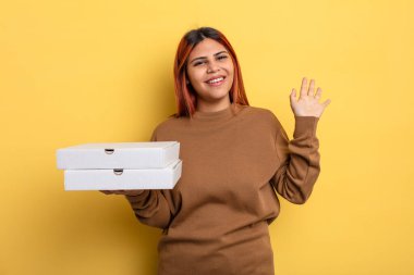 İspanyol kadın mutlu bir şekilde gülümsüyor, el sallıyor, sizi selamlıyor ve selamlıyor. Pizza konseptini kaldır.