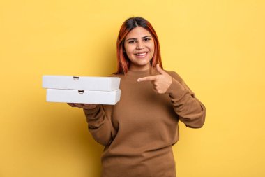 İspanyol kadın neşeyle gülümsüyor, mutlu hissediyor ve bir tarafı işaret ediyor. Pizza konseptini kaldır.