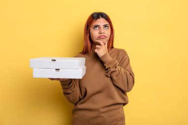 Hispanik kadın düşünüyor, kuşkulu ve şaşkın hissediyor. Pizza konseptini kaldır.