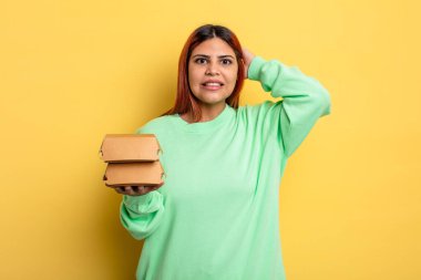 İspanyol kadın kendini stresli, endişeli ya da korkmuş hissediyor, elleri başının üstünde. Hamburger konseptini kaldır.
