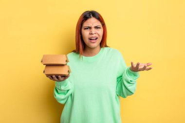 İspanyol kadın sinirli, sinirli ve hayal kırıklığına uğramış görünüyor. Hamburger konseptini kaldır.