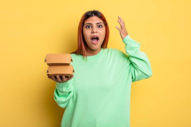 İspanyol kadın ellerini havaya kaldırarak çığlık atıyor. Hamburger konseptini kaldır.