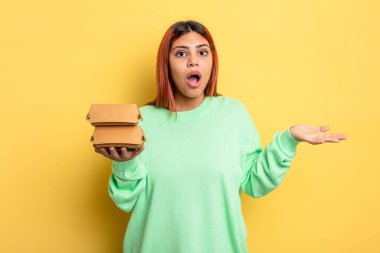 İspanyol kadın son derece şok olmuş ve şaşırmış hissediyor. Hamburger konseptini kaldır.