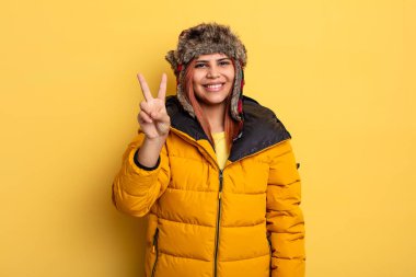 İspanyol kadın gülümsüyor ve arkadaş canlısı görünüyor, iki numarayı gösteriyor. kış konsepti